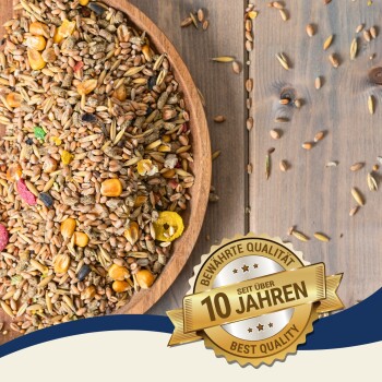 Eine Holzschüssel gefüllt mit buntem Vogelfutter, das Getreide, Mais und getrocknete Fruchtstücke enthält, mit einem Abzeichen, das "Beste Qualität - Seit 10 Jahren" besagt.