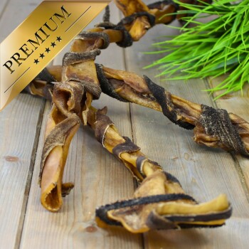 Premium-Hundekauartikel aus gedrehten Fleischstreifen, auf einer Holzoberfläche mit grünen Grasakzenten präsentiert.