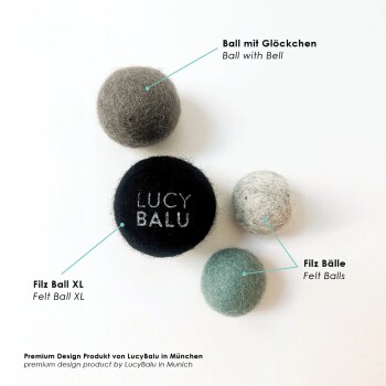 Vier Filzkugeln in verschiedenen Farben, darunter eine schwarze Kugel mit dem Text "LUCY BALU", beschriftet als "Ball mit Glöckchen" und "Filz Ball XL."