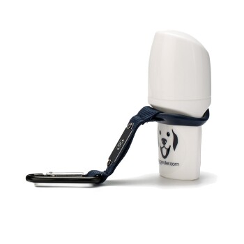 Ein brauner Hund legt seinen Kopf auf eine Holzoberfläche neben einer Flasche, die mit "Smoothie Dog Trinkpause" beschriftet ist, und einer tragbaren Wasserschüssel.