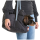 Eine Person in einem schwarzen Pullover hält eine gepolsterte Tragetasche für Haustiere, aus der der Kopf eines kleinen Hundes herausblickt, und zeigt ein komfortables Design.