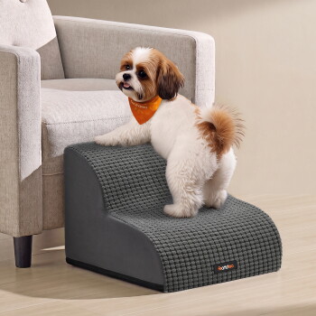 Kleiner flauschiger weiß-brauner Hund mit orangefarbener Bandana steht auf grauen Haustiertreppen mit 'feandrea'-Etikett.