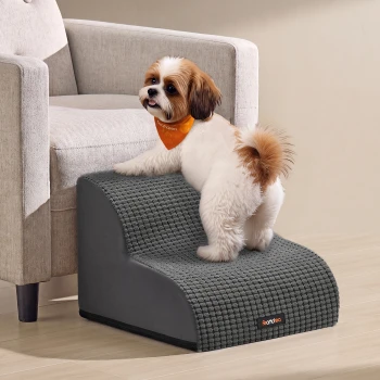 Kleiner flauschiger weiß-brauner Hund mit orangefarbener Bandana steht auf grauen Haustiertreppen mit 'feandrea'-Etikett.