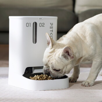 Eine weiße Französische Bulldogge frisst Trockenfutter aus einem weißen automatischen Futterspender mit der Beschriftung '01', '02' und 'PETKIT'.