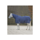 Ein weißes Pferd, das eine marineblaue Decke trägt, steht auf einer sandigen Fläche, umgeben von verschwommenem Grün im Hintergrund.