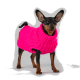 Ein kleiner Hund, der einen leuchtend pinken gestrickten Pullover trägt, steht vor einem schlichten grauen Hintergrund und zeigt sein stylisches Outfit.