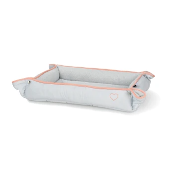 Jasnoszare legowisko dla zwierząt z miękkim wnętrzem i różowym wykończeniem, z małym wzorem serca po boku.