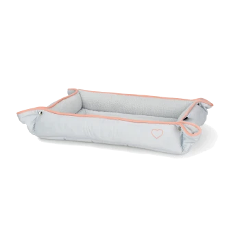 Lit pour animaux de compagnie gris clair avec un intérieur doux et une bordure rose, présentant un petit design en forme de cœur sur le côté.