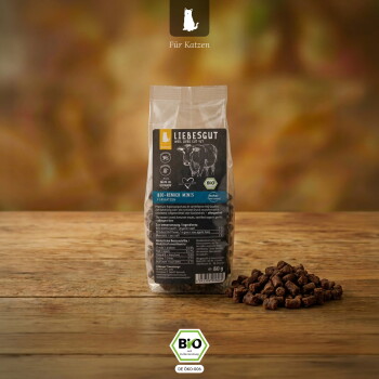 Tüte LIEBESGUT Bio-Rinder-Minis auf einem Holztisch mit einem Haufen Trockenfutter, Überschrift 'Für Katzen' und sichtbares BIO-Siegel.