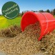 Roter Eimer gekippt, der Mischsaat auf Stroh in einem Feld verschüttet; grünes Abzeichen mit der Aufschrift ‚Tradionelle Mischung‘.