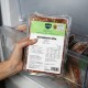 Hand hält vakuumversiegelte BARFER'S „Komplett‑Mix Lamm“ 500 g Rohfutterpackung in einem Gefrierschrank, Etikett und Fütterungstabelle sichtbar.