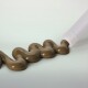 Eine Tube, die eine dicke, braune Paste in einer gewellten Linie auf einem hellen Hintergrund abgibt, wahrscheinlich ein Haustierfutter- oder Ergänzungsprodukt.