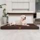 Ein weißer Hund, der auf einem braunen Haustierbett in einer modernen Küche mit minimalistischer Gestaltung und grünen Pflanzen im Hintergrund entspannt.