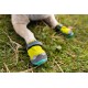 Nahaufnahme einer Hundepfote, die einen leuchtend gelben und grauen Hundestiefel auf Gras trägt, der sein schützendes Design zeigt.