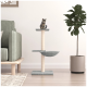 Eine getigerte Katze sitzt auf einem modernen, mehrstöckigen Katzenbaum mit einem Kratzbaum, der neben einem grünen Sofa und einer Topfpflanze positioniert ist.