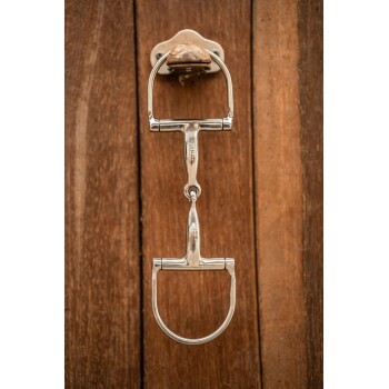 Ein glänzendes silbernes Pferdegebiss, das an einer Holzwand montiert ist, zeigt seine polierten Details und Handwerkskunst.