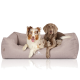 Zwei Hunde liegen zusammen auf einem weichen, beigen Haustierbett, auf dem das Logo "KNUFFELWUFF" sichtbar ist.
