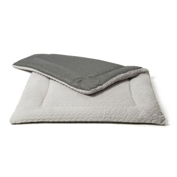 Ein gemütliches Haustierbett mit einer weichen, hellgrauen Basis mit plüschiger, gesteppten Textur und einer dunklen, glatten oberen Schicht.