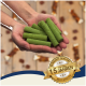 Hände halten grüne Kausticks, unscharfer Holzboden mit verstreuten Leckerlis und ein goldenes Abzeichen mit der Aufschrift '15 Jahren'.