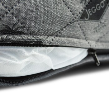 Nahaufnahme eines grauen Haustierbettes mit einem gesteppten Design und einem Reißverschluss, das eine weiße Innenauskleidung zeigt, die herausblitzt.