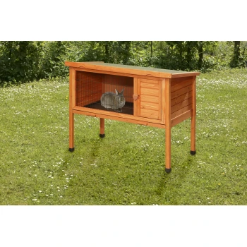 Une cabane en bois pour lapins avec un toit incliné, comportant une façade en treillis métallique et une petite porte, se trouve sur l'herbe avec un lapin à l'intérieur.