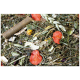 Eine Nahaufnahme einer Mischung aus getrockneten Kräutern und Blumen für Haustiere, mit grünem Gras, roten Blütenblättern, gelben Blumen und einem kleinen Zweig.