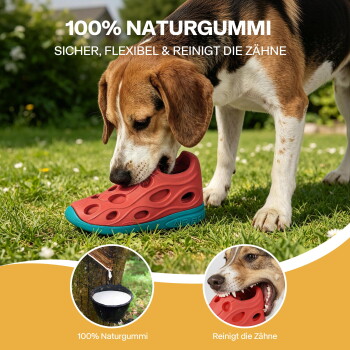 Hund kaut auf einem roten Gummischuh-Spielzeug im Gras; sichtbarer Text: '100% NATURGUMMI' und 'SICHER, FLEXIBEL & REINIGT DIE ZÄHNE'.