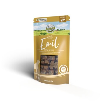 Eine goldene Verpackung von "Emil Silky Gloss" Hundesnacks, mit einer malerischen ländlichen Kulisse, mit dem Text, der angibt, dass es sich um einen weichen Snack handelt und 100 % natürlich ist.