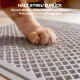 Orangene Katzenpfote auf einer grauen geriffelten Streufangmatte mit verstreutem Katzenstreu; sichtbarer Text 'HÄLT STREU ZURÜCK'.