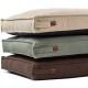 Gestapeltes Set aus drei rechteckigen Haustierbetten in Beige, Salbeigrün und Braun mit Seitengriffen und kleinen braunen Lederetiketten.