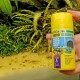 Une main tenant un contenant jaune de nourriture pour poissons 'PRO JBL NOVO SHRIMPS', avec un texte visible en plusieurs langues et un fond d'aquarium verdoyant.