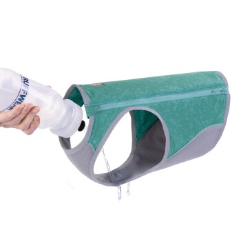 Eine Hand hält eine Wasserflasche, die Wasser in eine grüne Haustier-Hydrationsweste mit grauen Netzseiten gießt, entworfen für den Außeneinsatz.