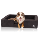 Ein glücklicher Australian Shepherd Hund, der auf einem stilvollen schwarzen Hundebett mit erhöhtem Rand liegt, das das Markenlogo "KNUFFELWUFF" zeigt.