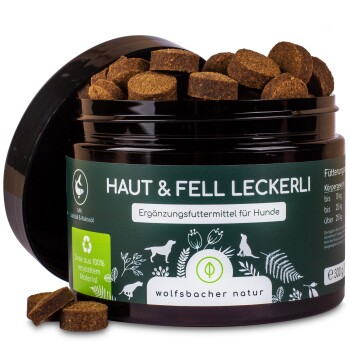 Schwarzes Glas mit 'Haut & Fell Leckerli' Hundefutterergänzung mit braunen Leckereien darin, mit grünem Etikett mit Recycling-Symbol und Fütterungsanweisungen.