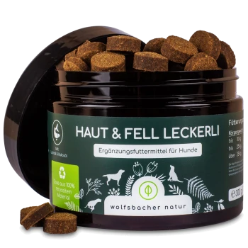 Schwarzes Glas mit 'Haut & Fell Leckerli' Hundefutterergänzung mit braunen Leckereien darin, mit grünem Etikett mit Recycling-Symbol und Fütterungsanweisungen.