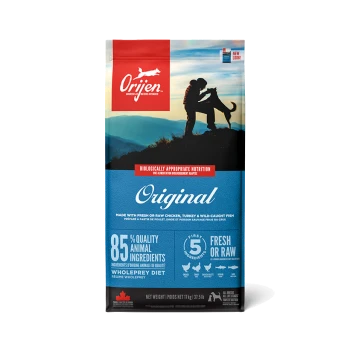 Sac de nourriture pour chiens Orijen Original avec un couple et un chien devant des montagnes, mettant en avant "85% d'ingrédients animaux de qualité" et "frais ou cru."