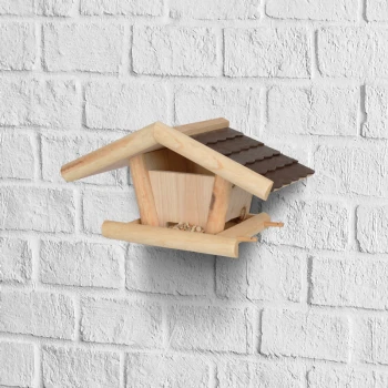 Nichoir en bois avec un toit incliné, monté sur un mur en briques blanches, comportant une petite zone d'alimentation à la base.