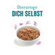 Schüssel mit Haustierfutter mit gemischten Zutaten, begleitet von dem Text "Überzeuge DICH SELBST" in einer verspielten Schriftart.