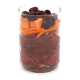 Ein klares Glasgefäß, gefüllt mit Schichten aus getrocknetem Fleisch, orangefarbenen Karottenstreifen, roten Apfelstücken und dunklen getrockneten Beeren, mit Leinsamen am Boden.