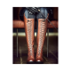 Eine Nahaufnahme einer Person, die mit gekreuzten Beinen sitzt und hohe, braune Lederreitstiefel mit aufwendiger Schnürung und schwarze Handschuhe trägt.