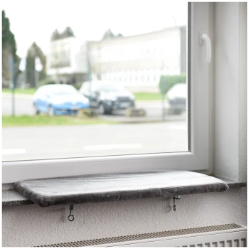 Eine graue Katzenfensterliege, die auf einer Fensterbank montiert ist, mit Blick auf geparkte Autos und ein Gebäude draußen.