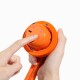 Hände halten ein orangefarbenes Spielzeug mit Stoffgriff zum Apportieren; ein Finger drückt den Einschaltknopf, blaues LED leuchtet und der USB‑C‑Ladeanschluss ist sichtbar.