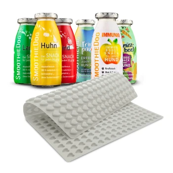 Bunte Smoothieflaschen für Hunde, beschriftet mit Geschmacksrichtungen wie "Huhn" und "Rind", neben einer rosa Silikonmatte mit Herzformen.