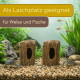 Aquarium mit zwei hohlen Baumstamm-Höhlen auf Kies, Fische und Flusskrebs; Text: 'Als Laichplatz geeignet' 'für Welse und Fische'