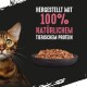Eine Nahaufnahme des Gesichts einer Bengalkatze neben einer Schüssel mit Katzenfutter, mit dem Text "HERGESTELLT MIT 100% NATÜRLICHEM TIERISCHEM PROTEIN."