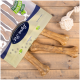 Eine Packung Hundekau-Knochen mit der Aufschrift "Pet Set" und einem Logo, mit drei Knochen auf einer Holzoberfläche und einem Seilspielzeug in der Nähe.