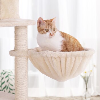 Eine gemütliche beige Katzenhängematte, die an einem Kratzbaum befestigt ist, mit einer orange-weißen Katze, die bequem darin ruht.