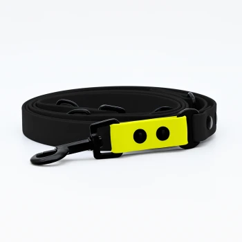 Biothane Hundeleine Schwarz neon gelb Schwarze Haustierleine mit einem leuchtend gelben Griff mit zwei Löchern, auf einem weißen Hintergrund aufgewickelt.
