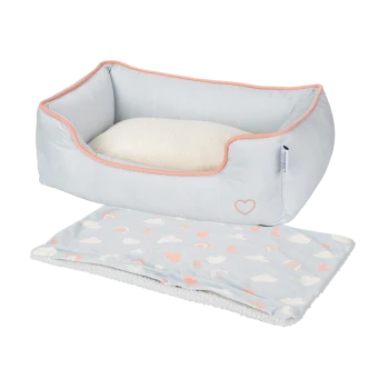 Lit pour animaux de couleur bleu clair avec un coussin crème doux et une couverture assortie présentant des cœurs colorés et des arcs-en-ciel.