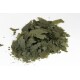 Ein Haufen grüner, blättriger Flocken, die getrocknetem Algen oder Spirulina ähneln, vor einem weißen Hintergrund.